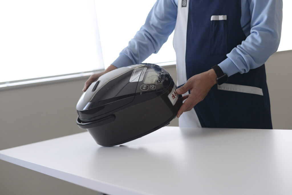 炊飯器の傷を確認するスタッフ