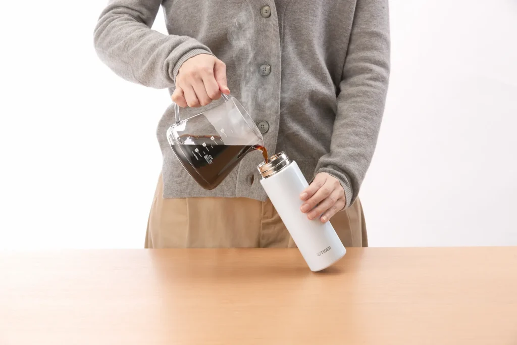 Pouring coffee into her bottle.