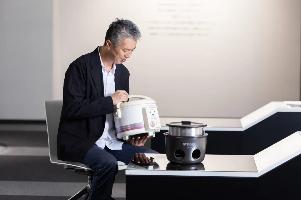 Mr. Murata holding an old rice cooker.