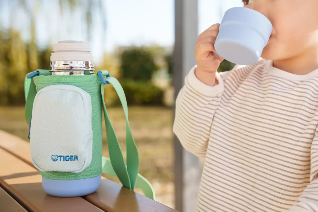 An elementary school girl drinking water from a bottle.